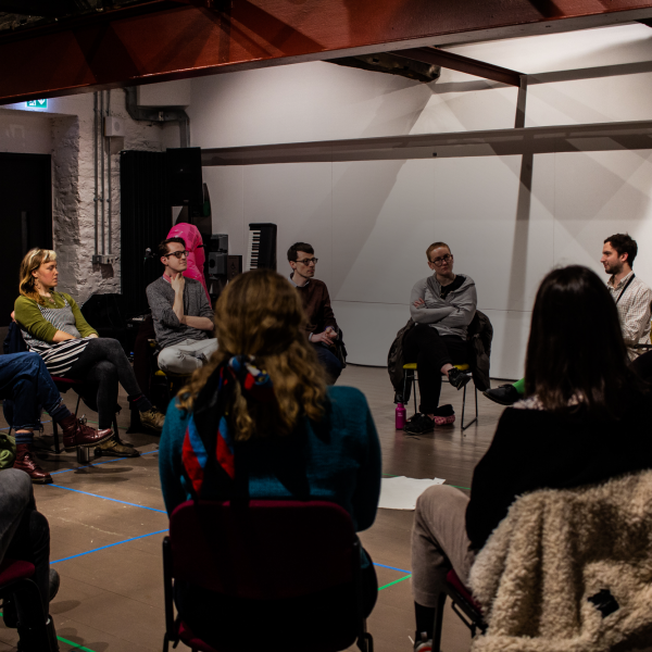 An image of artists sat in a circle in conversation