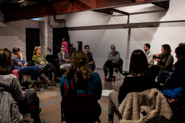 An image of artists sat in a circle in conversation