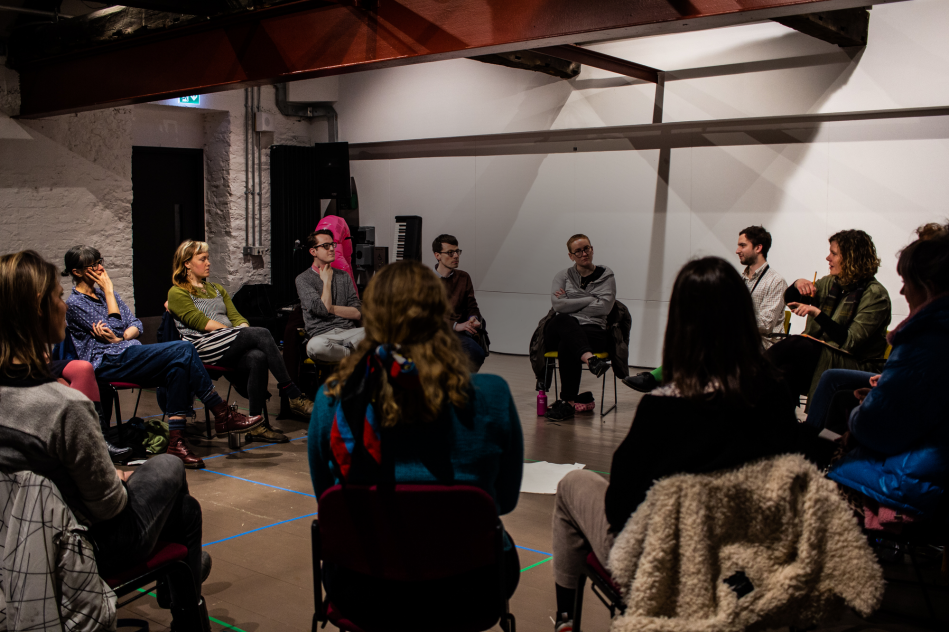 An image of artists sat in a circle in conversation